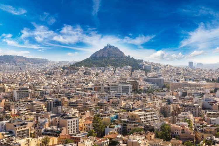 Steep cone-shaped rocky hill rises above the city quarters of Athens